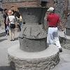 The stone object is a grinder that was used to make flour - for bread which was baked in the ovens in the rear.